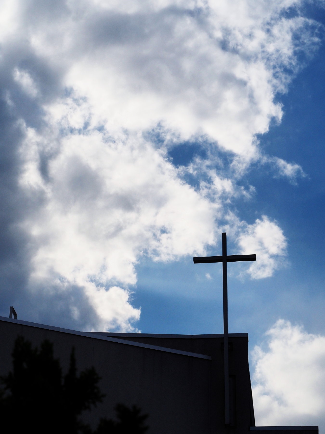 空を覆う雲に毅然として立つ教会十字架