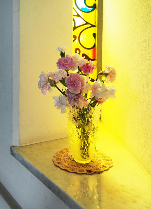 階段踊り場のステンドグラス前に置かれた花瓶に活けられたカーネーション