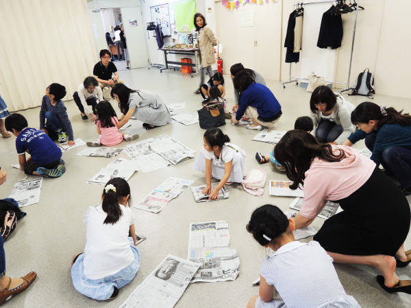 新聞紙でカブトを作る子どもたち