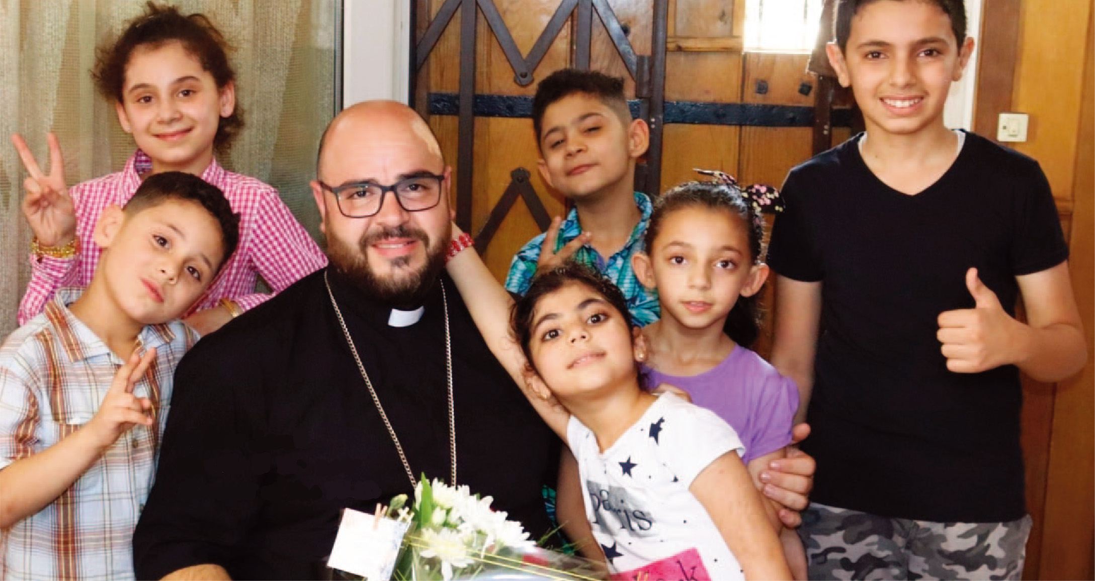 2022年に「聖地ろうあ子どもの里」のNew Directorに就任されたJamil Khadir神父と子どもたちの写真。Jamil神父が6人の子どもたちに囲まれている。みな楽しそう。